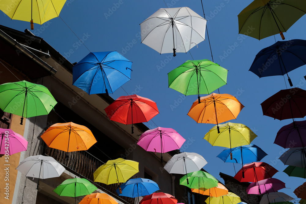 Aufgehängte Regenschirme in der Fußgängerzone in Embrun in Frankreich an einem Tag mit blauen Himmel  