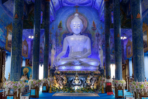 white buddha on a blue background meditating at Wat Rong Suea Ten Chiang Rai photo