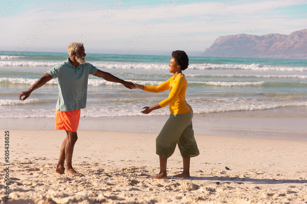 Φωτογραφία Bearded african american senior man dancing with mature woman against seascape a