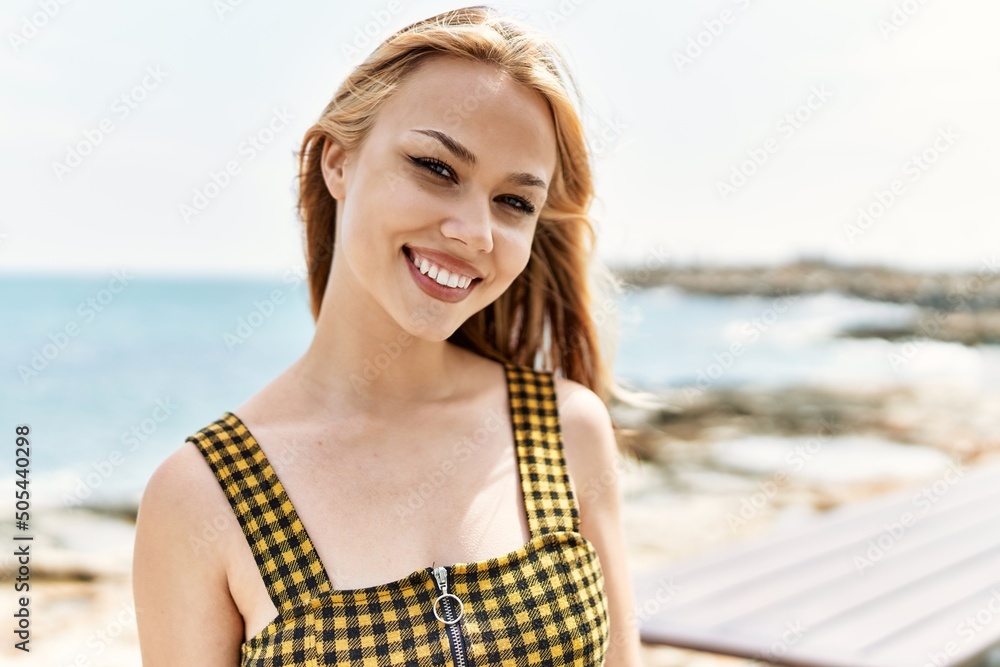 Young caucasian girl smiling happy standing at the beach.