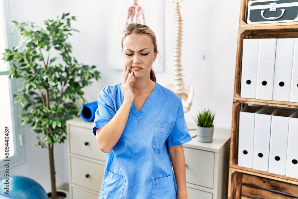 Young caucasian woman working at pain recovery clinic touching mouth with hand with painful expression because of toothache or dental illness on teeth. dentist Young caucasian woman working at pain recovery clinic touching mouth with hand with painful expression because of toothache or dental illness on teeth. dentist
