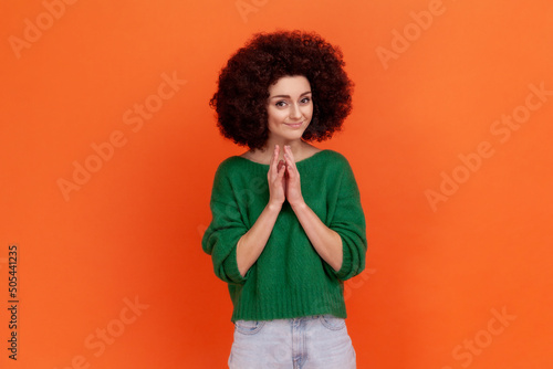 Foto Cunning young adult woman with Afro hairstyle wearing green casual style sweater having tricky plans, looking at camera with cheating face