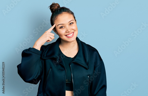 Young hispanic girl wearing sportswear smiling pointing to head with one finger, great idea or thought, good memory photo