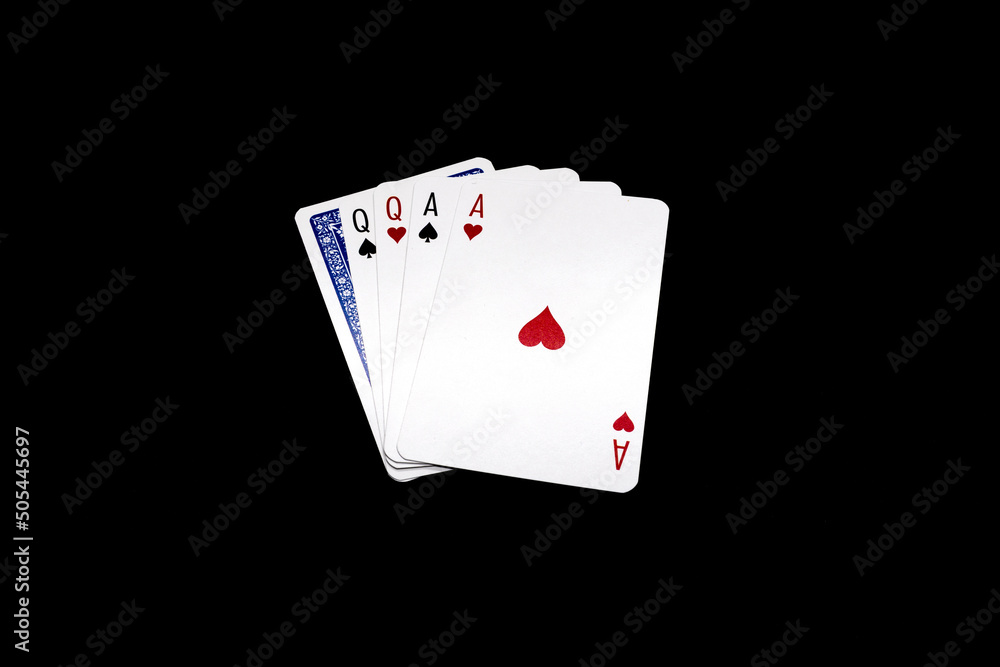 Two pair of queens and aces  with one overturned card.  Poker hand isolated on black background