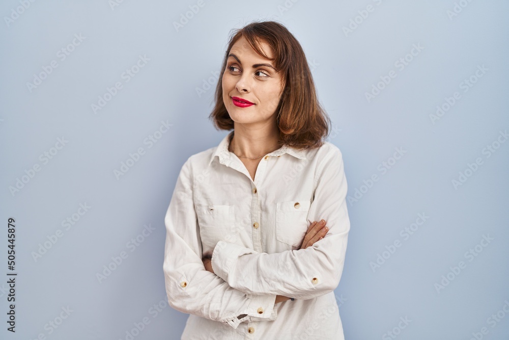 Young beautiful woman standing casual over blue background smiling looking to the side and staring away thinking. Young beautiful woman standing casual over blue background smiling looking to the side and staring away thinking.