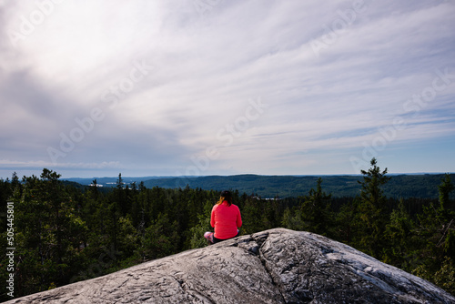 Woman sitting on a rock with beautiful summer landscape from Ukko-Koli, Koli National Park in Finland photo