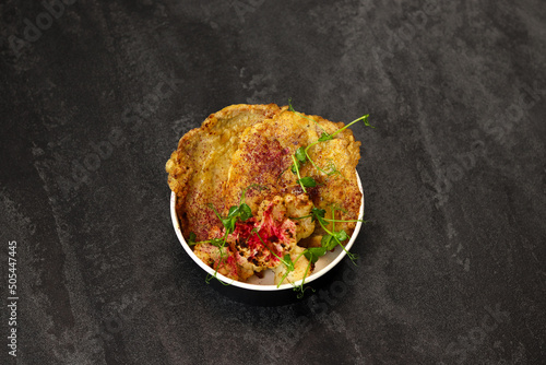 Healthy food delivery concept. Beef schnitzel with cauliflower in an eco paper container on a black background. Restaurant dish delivery. Top view. Free space for text