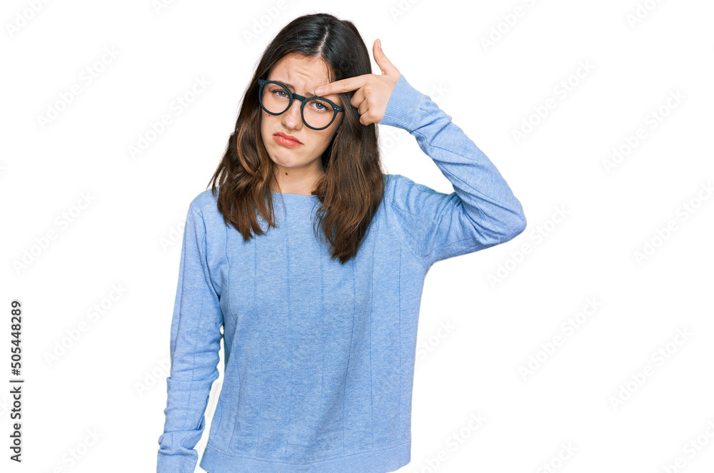 Young beautiful woman wearing casual clothes and glasses pointing unhappy to pimple on forehead, ugly infection of blackhead. acne and skin problem