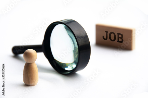 Selective focus of wooden doll looking through magnifying glass seeking for job. photo