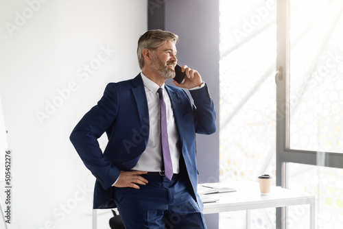 Business Call. Confident Middle Aged Businessman Talking On Cellphone At Office