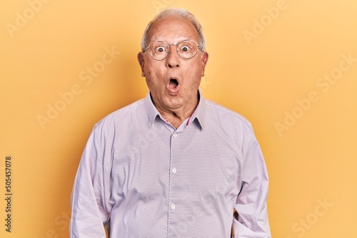 Senior man with grey hair wearing elegant shirt and glasses scared and amazed with open mouth for surprise, disbelief face © Krakenimages.com