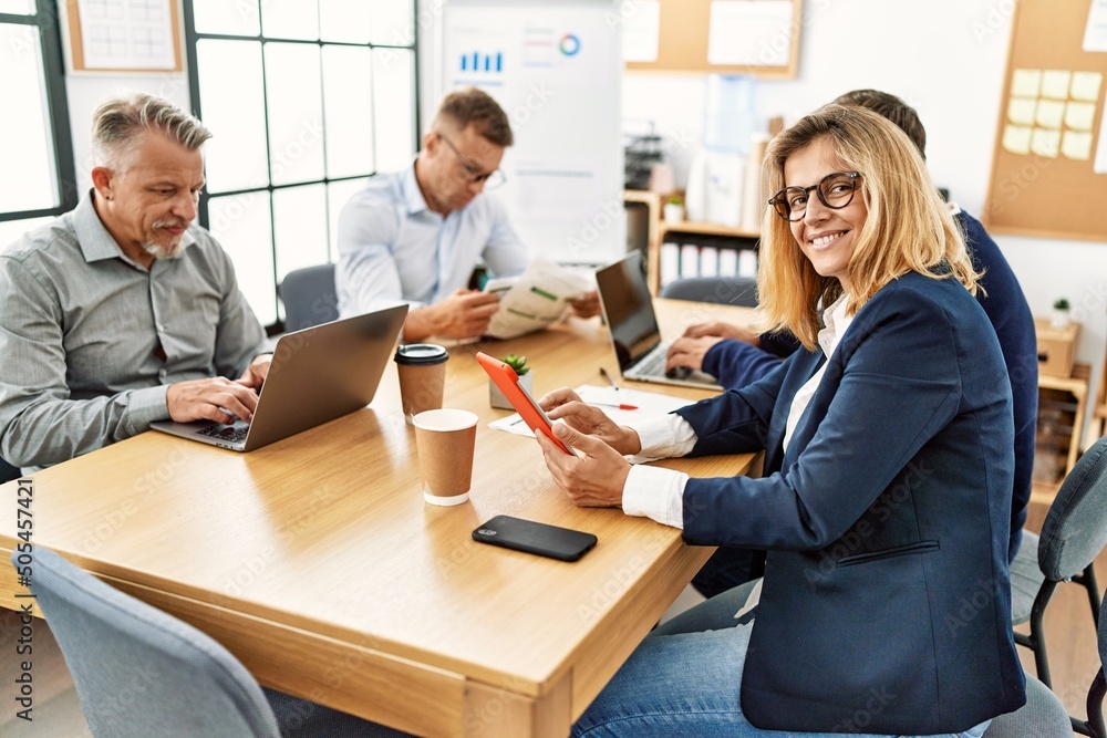 Group of middle age business workers working. Woman smiling happy and looking to the camera at the office. Group of middle age business workers working. Woman smiling happy and looking to the camera at the office.