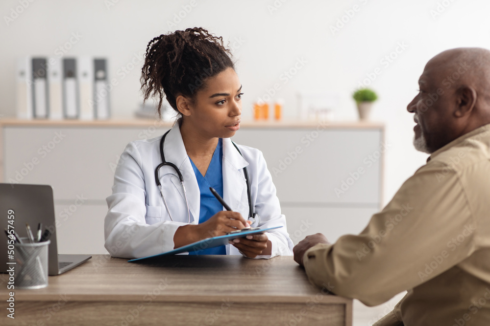 Young black doctor writing personal information, filling form Young black doctor writing personal information, filling form
