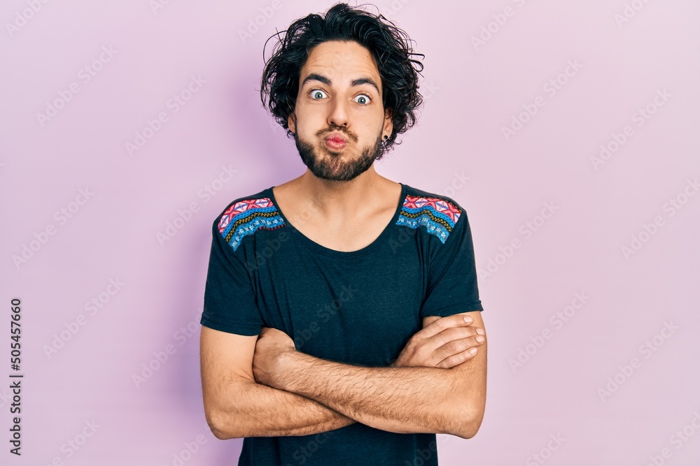 Handsome hispanic man with arms crossed gesture puffing cheeks with funny face. mouth inflated with air, catching air. Handsome hispanic man with arms crossed gesture puffing cheeks with funny face. mouth inflated with air, catching air.