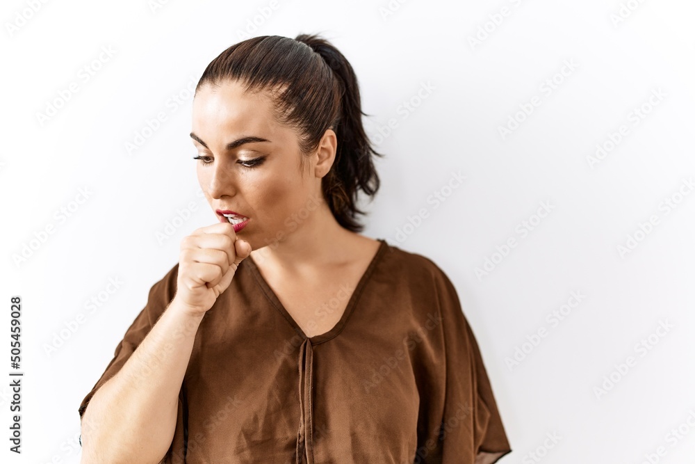 Young brunette woman standing over isolated background feeling unwell and coughing as symptom for cold or bronchitis. health care concept. Young brunette woman standing over isolated background feeling unwell and coughing as symptom for cold or bronchitis. health care concept.