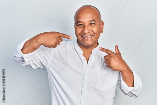 Middle age latin man wearing casual clothes smiling cheerful showing and pointing with fingers teeth and mouth. dental health concept.