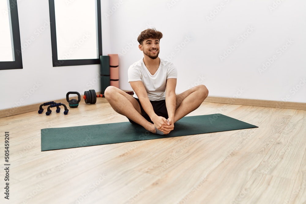 Fototapeta premium Young arab man smiling confident stretching at sport center