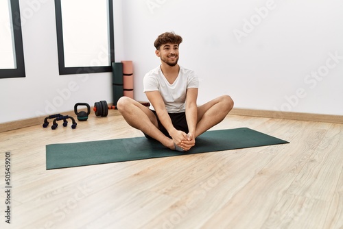 Young arab man smiling confident stretching at sport center