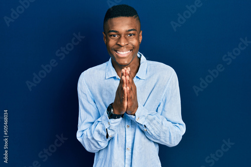 Young african american man wearing casual clothes praying with hands together asking for forgiveness smiling confident.