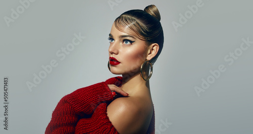 Portrait of a beautiful young tanned woman with a smooth hairstyle and bright red lips. The model poses in a red knitted dress. Advertising of fashionable clothes. Advertisement of decorative cosmetic