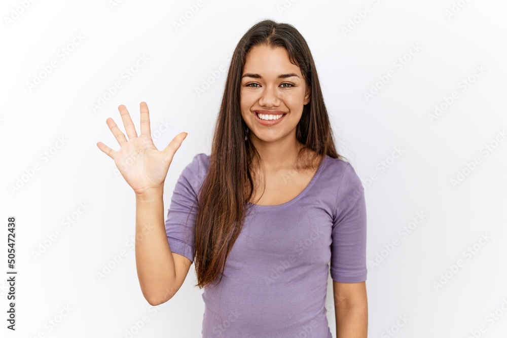 Young brunette woman standing by isolated background showing and pointing up with fingers number five while smiling confident and happy. Young brunette woman standing by isolated background showing and pointing up with fingers number five while smiling confident and happy.