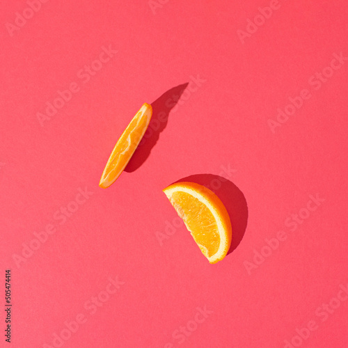 Orange slace on vibrant pink background.  Minimal summer fruit or organic food concept. photo