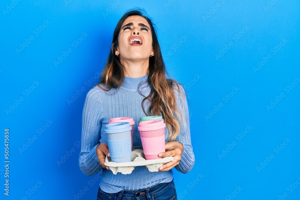 Young hispanic girl holding tray with take away coffee angry and mad screaming frustrated and furious, shouting with anger looking up. Young hispanic girl holding tray with take away coffee angry and mad screaming frustrated and furious, shouting with anger looking up.