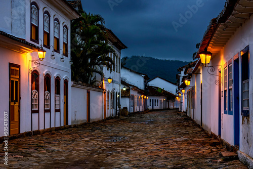 Streets and houses of the historic city of Paraty in the state of Rio de Janeiro illuminated at dusk with the mountains in the background photo
