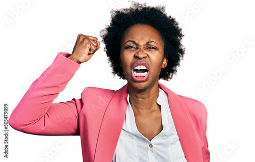 African american woman with afro hair wearing business jacket angry and mad raising fist frustrated and furious while shouting with anger. rage and aggressive concept. photo