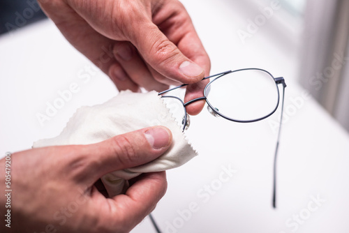 Man wiping lens glasses with special fiber cloth.