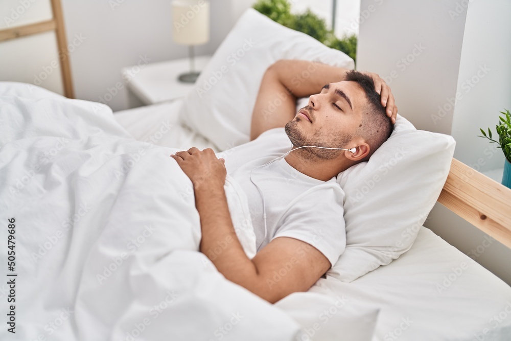 Εκτύπωση καμβά Young hispanic man listening to music lying on bed at bedroom