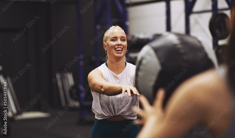 Smiling woman exercising with a partner using a medicine ball Smiling woman exercising with a partner using a medicine ball