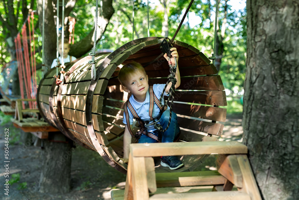 Little active boy who climbs on a rope the way to the amusement Park in the summer Little active boy who climbs on a rope the way to the amusement Park in the summer