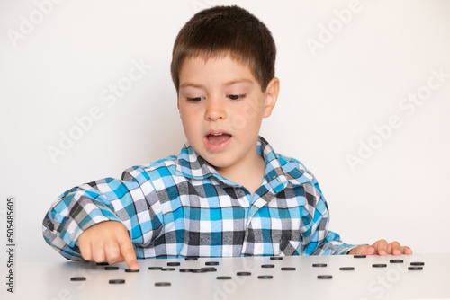 A 4-year-old boy is learning to count, teaching black numeracy chips for preschoolers photo
