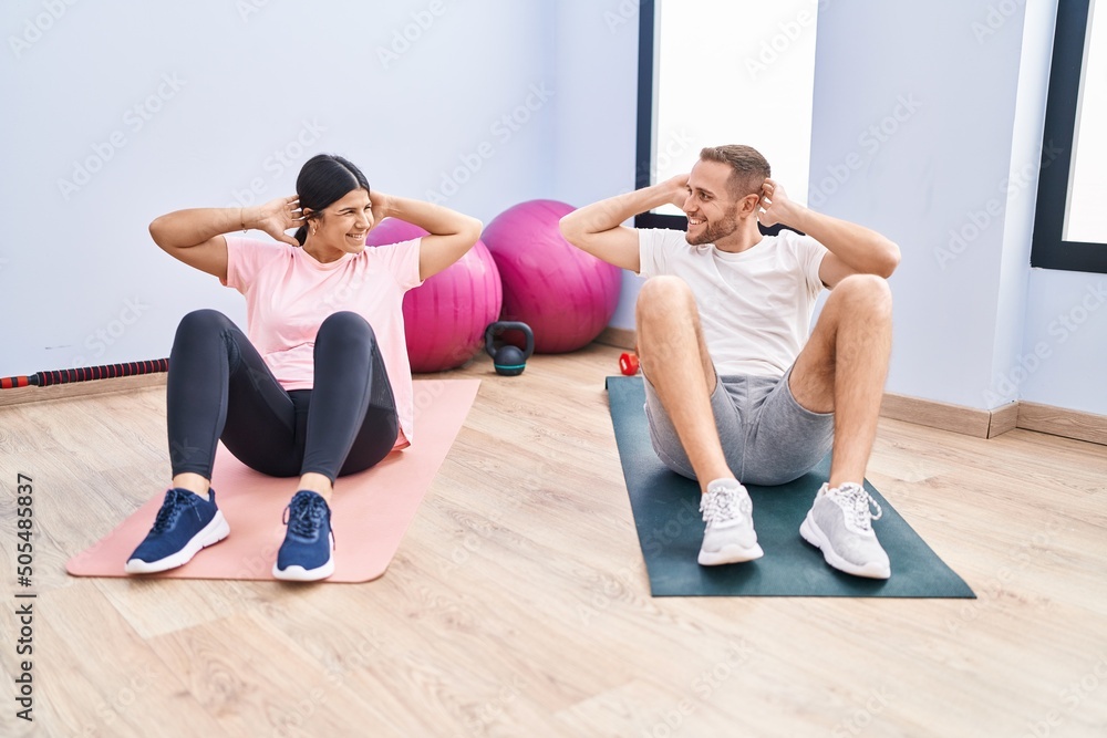 Man and woman couple smiling confident training abs exercise at sport center Man and woman couple smiling confident training abs exercise at sport center