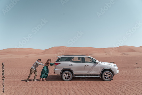 Couple pushing the 4x4 car in the desert of Oman.
