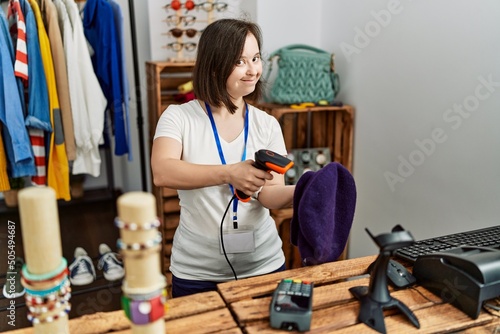 Brunette woman with down syndrome working as shop assistant selling hat at retail shop