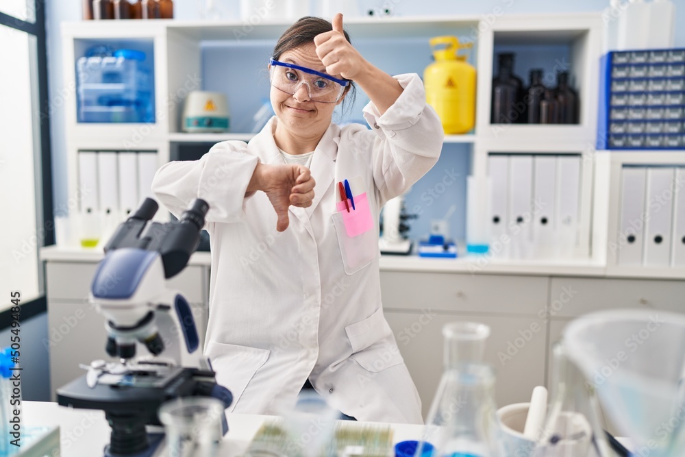 Hispanic girl with down syndrome working at scientist laboratory doing thumbs up and down, disagreement and agreement expression. crazy conflict Hispanic girl with down syndrome working at scientist laboratory doing thumbs up and down, disagreement and agreement expression. crazy conflict