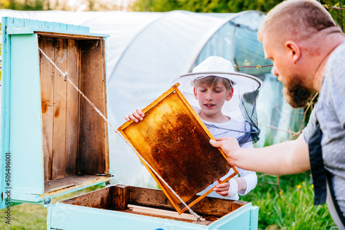Father beekeeper passes his experience son. Family small business. Bees, honey, hive, children. Beekeeping concept photo