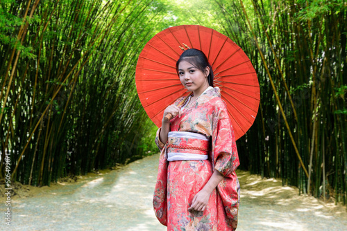 A woman in a kimmono dress holds an umbrella in a bamboo grove in Japan. Major tourist attractions in Japan.