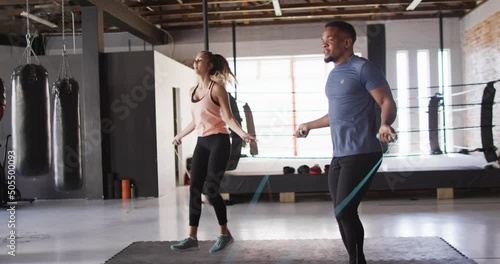 Video of fit diverse woman and man jumping on jumping rope at gym