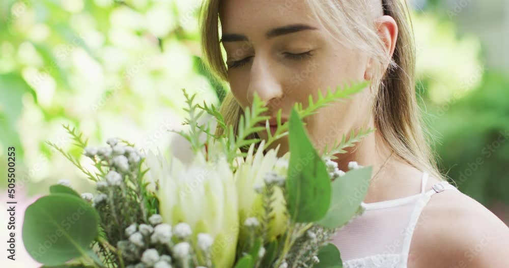 Happy caucasian woman holding bunch of flowers in garden on sunny day Happy caucasian woman holding bunch of flowers in garden on sunny day