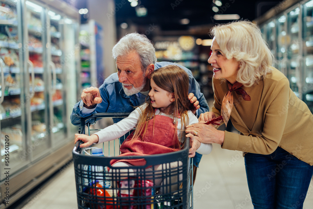 Happy grandparents and grandchild shopping at supermarket