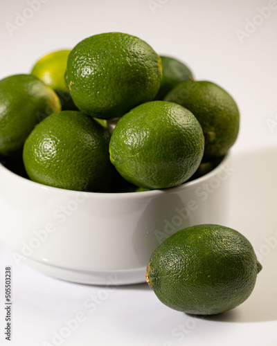White bowl of limes on a white surface