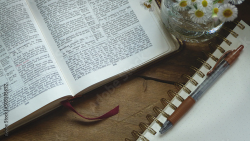 Rustic Bible with a Notepad and a Jar of Flowers on a Wooden Background 
