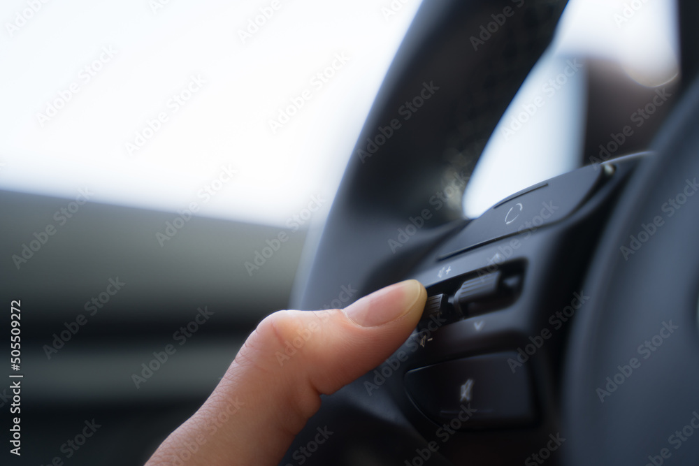 Person presses the button on the steering wheel of the car, close-up. Volume control in the car. The concept of modern technologies in road traffic Person presses the button on the steering wheel of the car, close-up. Volume control in the car. The concept of modern technologies in road traffic