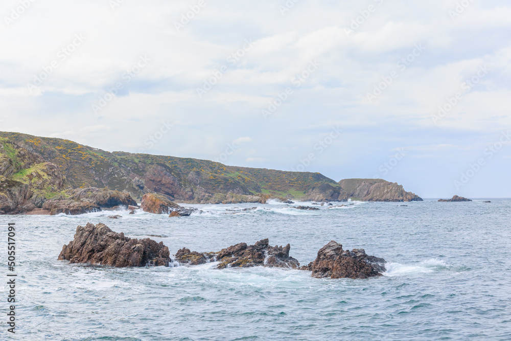 A scenic view of a rocky coastal landscape with huge cliffs under a majestic blue sky
