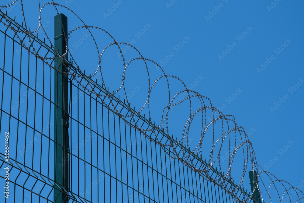 razor wire fence. blue sky background.