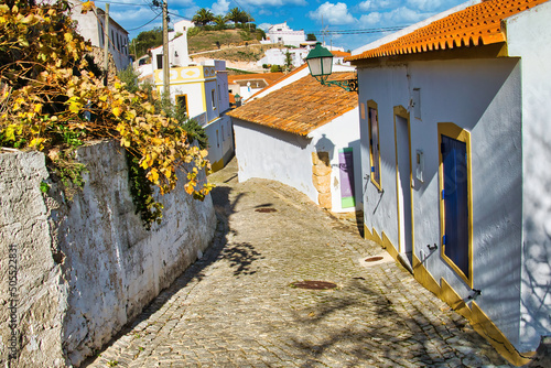 Steep cobblestoned street with whitewashed houses in the old town of Aljezur, Algarve, Portugal
