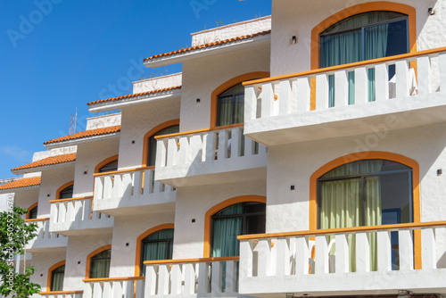 Balconies and blue sky. Part of a residential building in Mexico. Modern apartment buildings on a sunny day. Architectural details. The facade of the hotel is in the colonial style.